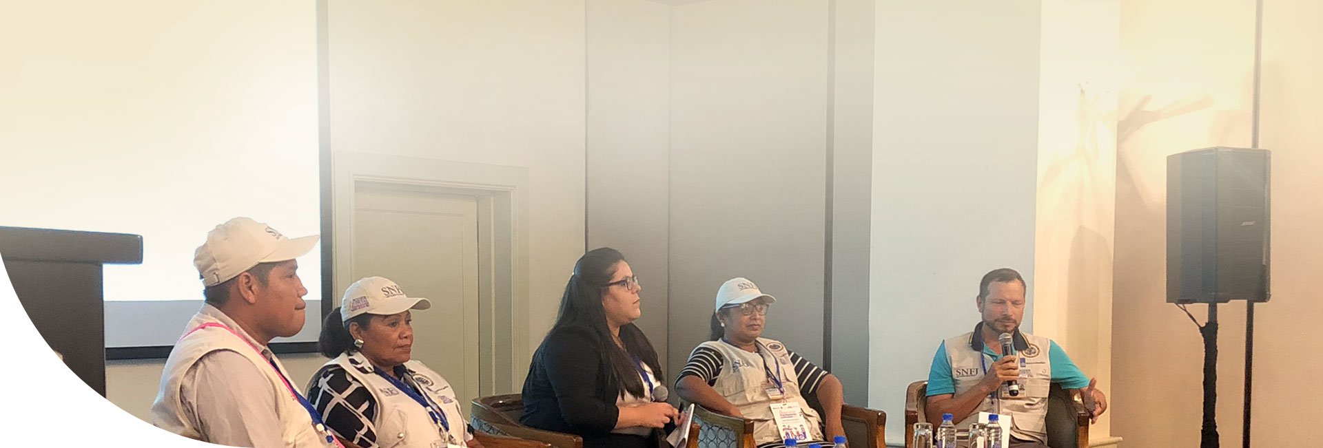 Facilitadores y facilitadoras judiciales sentados conversando en un escenario