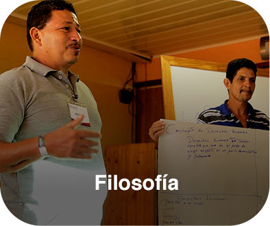 Dos hombres de pie exponiendo, uno de ellos sostiene un cartel